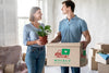 Couple Holding Plants And Box With Objects For Their New Home Psd