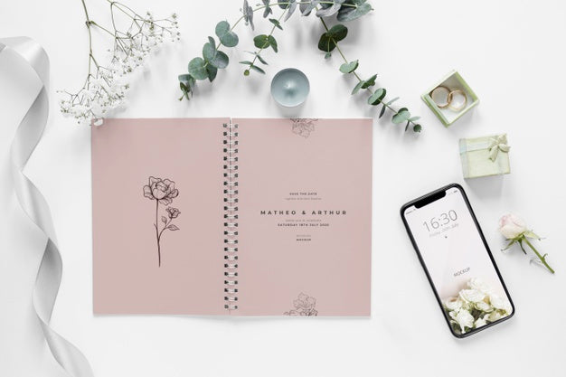 Fat Lay Of Wedding Notebook With Smartphone And Plants Psd