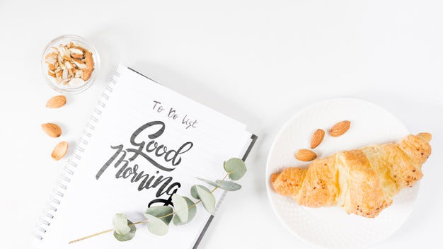 Flat Lay Of Notebook Next To Croissant Psd