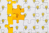 Flat Lay Puzzle With Light Bulbs On Yellow Background Psd