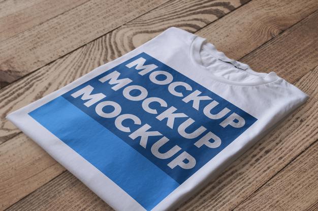 Folded White T-Shirt Over Wood Surface Mockup Psd