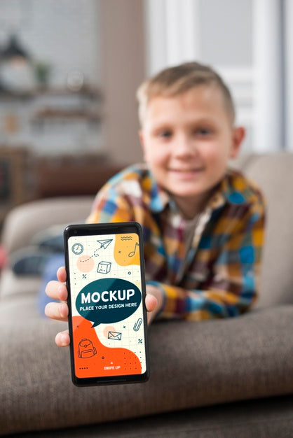 Front View Of Defocused Kid On Couch Holding Smartphone Psd