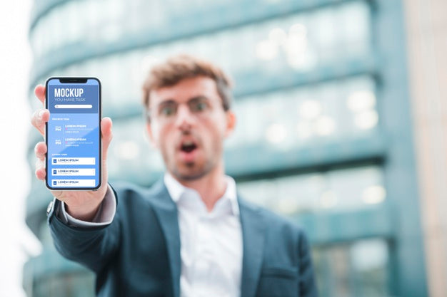Front View Of Shocked Businessman Holding Smartphone Psd