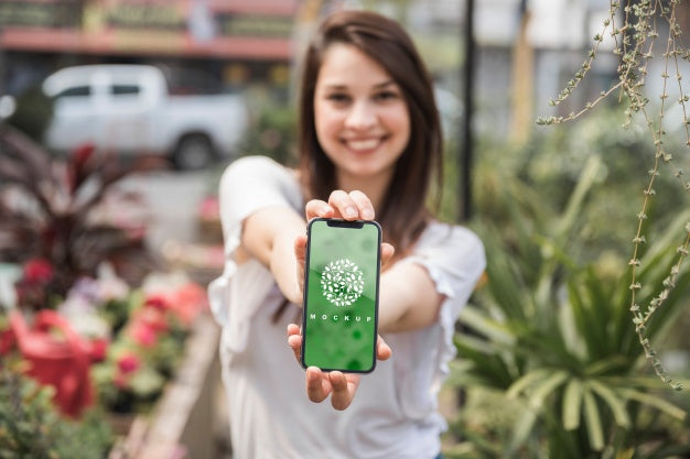 Girl Holding Smartphone Mockup With Gardening Concept Psd