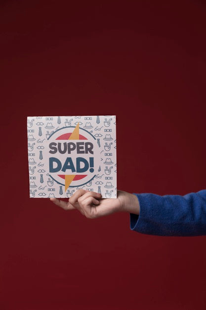 Hand Holding Cardboard Mock-Up On Burgundy Background Psd