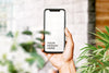 Hand Holding New Smartphone Mockup Surrounded By Leaves Psd
