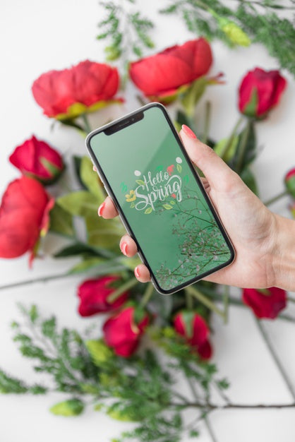 Hand Holding Smartphone Mockup Above Flowers Psd