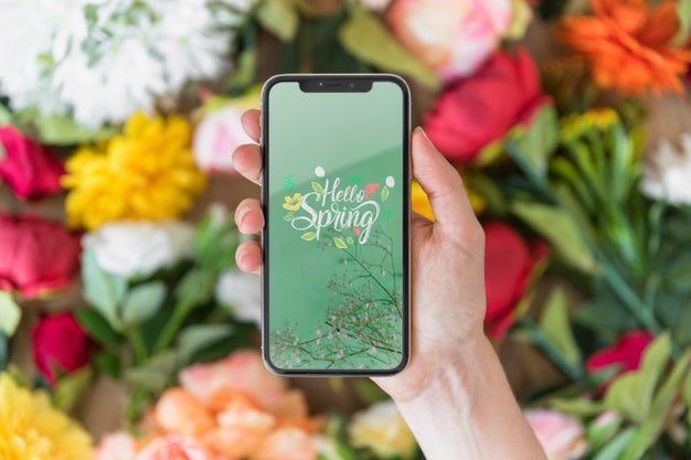 Hand Holding Smartphone Mockup Above Flowers Psd