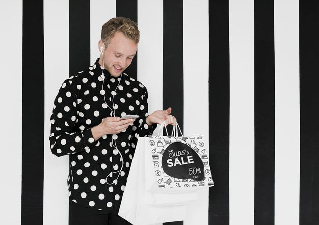 Happy Man With Shopping Bags Looking At Mobile Psd