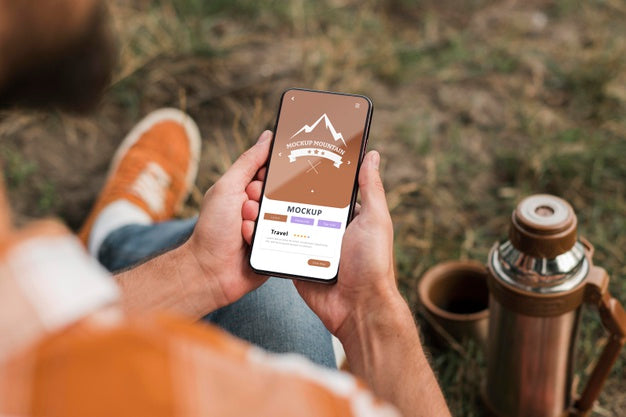 High Angle Of Man Holding Smartphone While Camping Psd