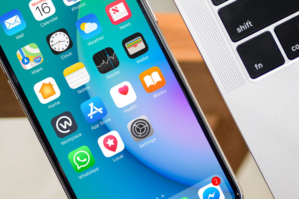 Black iPhone X on Glass Table with Macbook Pro PSD Mockup