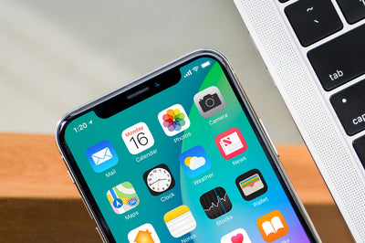 Black iPhone X on Glass Table with Macbook Pro PSD Mockup