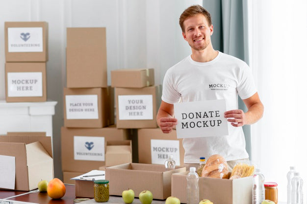 Male Volunteer Holding Blank Paper With Food Boxes For Donation Psd