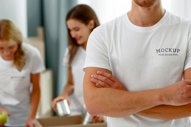 Male Volunteer Posing With Arms Crossed While Colleagues Prepare Donation Boxes With Food Psd