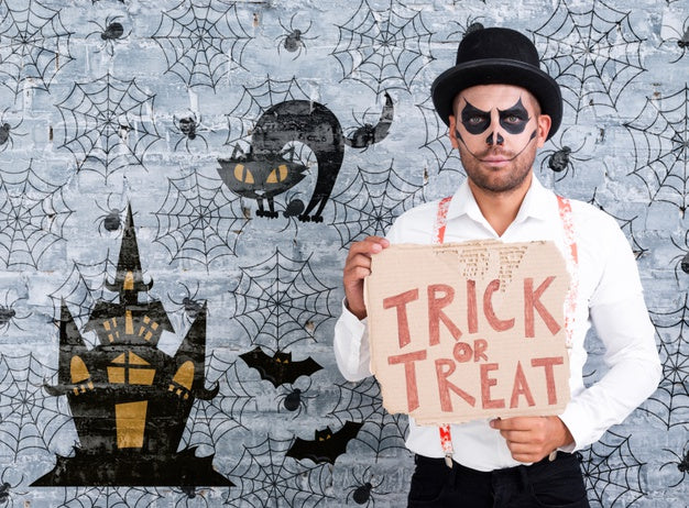 Male With Make-Up Holding A Card With Trick Or Treat Lettering For Halloween Psd