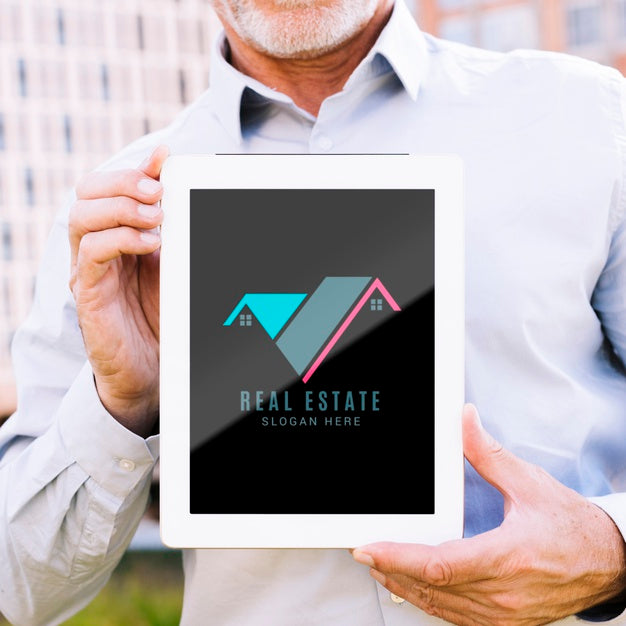 Man Holding A Tablet Mock-Up With A Real Estate Business Psd