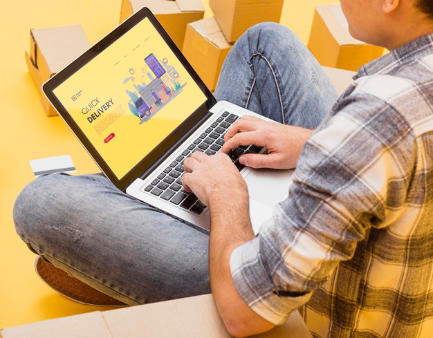 Man Holding Laptop Mock-Up Around Parcels Psd