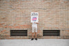 Man Holding Poster Mockup In Front Of Brick Wall Psd