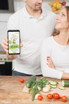 Man Holding Smartphone In The Kitchen While Cooking With Woman Psd