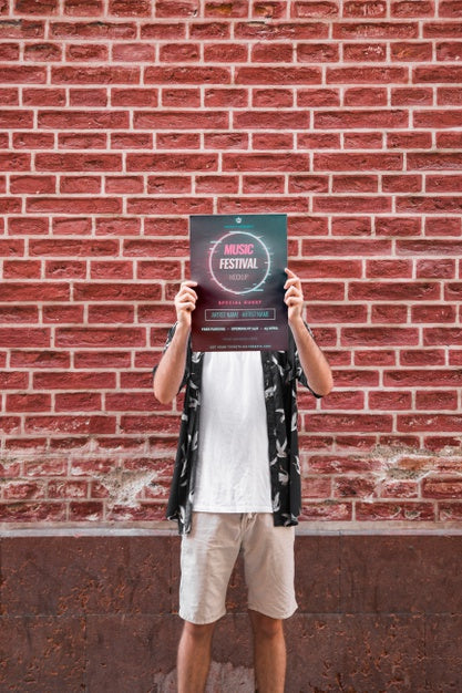 Man Presenting Poster Mockup In Front Of Brick Wall Psd