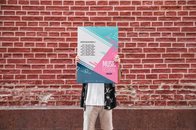 Man Presenting Poster Mockup In Front Of Brick Wall Psd