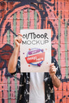 Man Presenting Poster Mockup In Front Of Graffiti Wall Psd