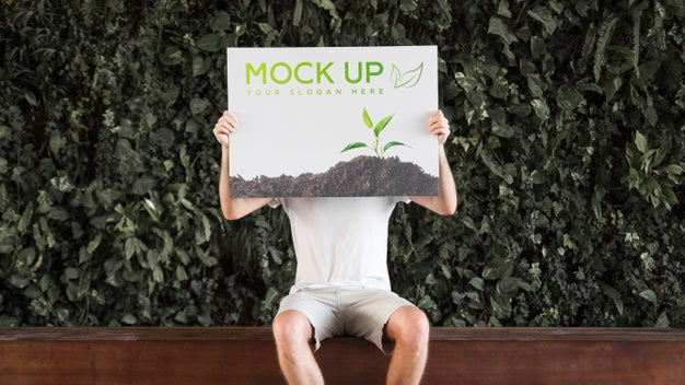 Man Presenting Poster Mockup In Front Of Leaves Psd