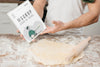 Man Rolling Dough In The Kitchen And Holding Book Psd