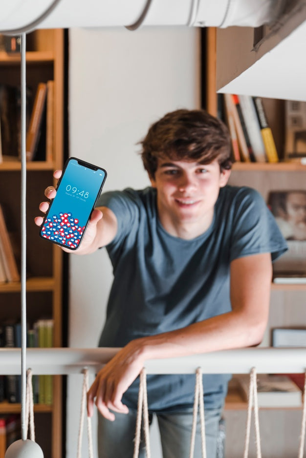 Man Showing Smartphone Mockup In Library Psd
