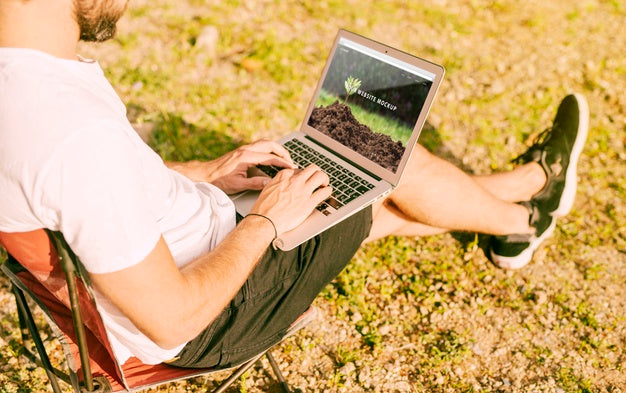 Man Using Laptop Mockup In Nature Psd