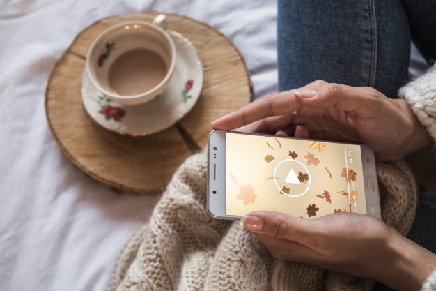 Person On Bed Looking At Smartphone With Autumn Concept Psd