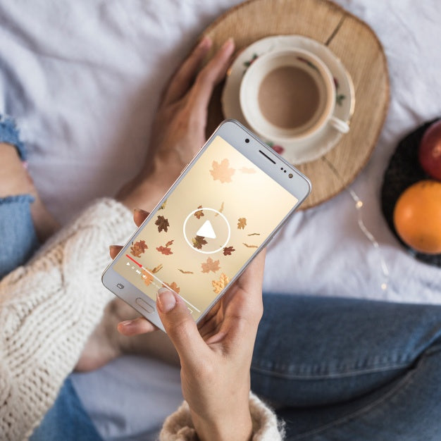 Person On Bed Looking At Smartphone With Autumn Concept Psd