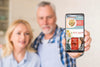 Senior Couple In Kitchen Holding Smartphone Mock-Up Psd