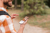 Side View Of Smiley Man Holding Smartphone While Camping Psd
