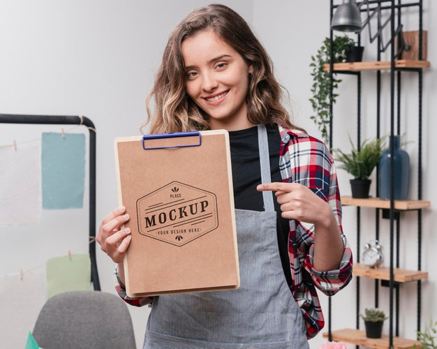Smiley Female Artist Holding Mock-Up Notepad And Pointing At It Psd