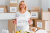 Smiley Female Volunteer Holding Blank Paper Next To Food Box Psd