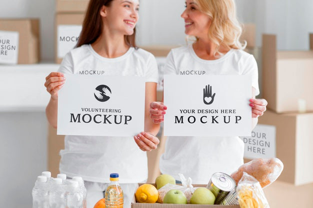 Smiley Female Volunteers Holding Blank Papers Next To Food Box Psd