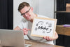 Smiley Man Holding Mock-Up Frame With Open Laptop Psd
