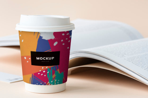Takeaway Coffee Cup Mockup On A Table With An Open Book Psd