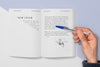 Top View Hand Holding Pen Over Open Book Mock-Up Psd