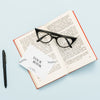 Top View Of Open Book With Glasses And Card Psd