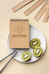 Top View Of Paper Stationery On Plate With Kiwi And Pencils Psd