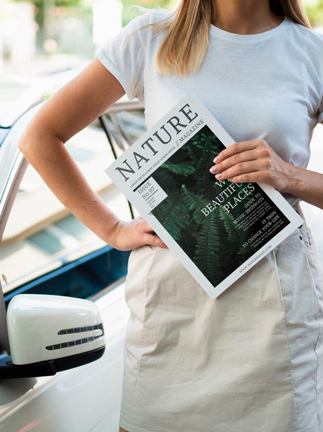 Woman Holding A Nature Magazine Next To A Car Psd