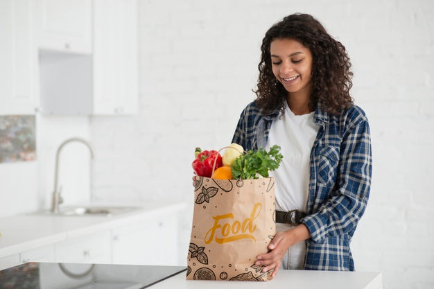 Woman In Kitchen With Bag Of Fresh Vegetables Psd