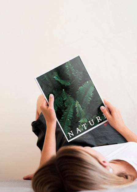 Woman Lain Down And Holding A Nature Magazine Psd