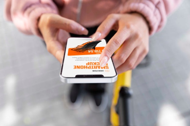 Woman Using Mock-Up Smartphone Outdoors While On Bicycle Psd