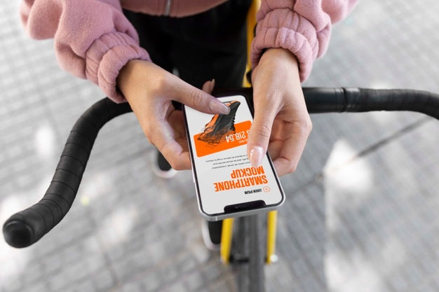 Woman Using Mock-Up Smartphone Outdoors While On Bicycle Psd