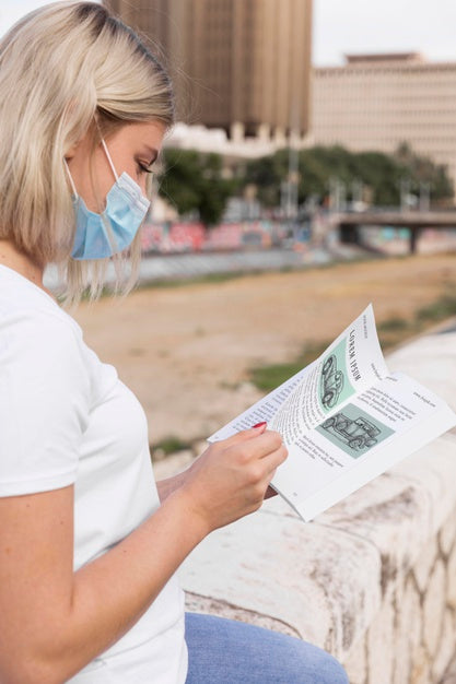 Woman With Mask Reading Book On Street Psd