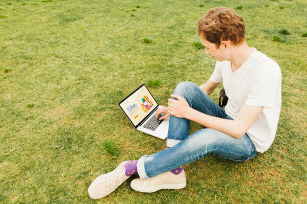 Young Male Working On Laptop Outdoors Psd