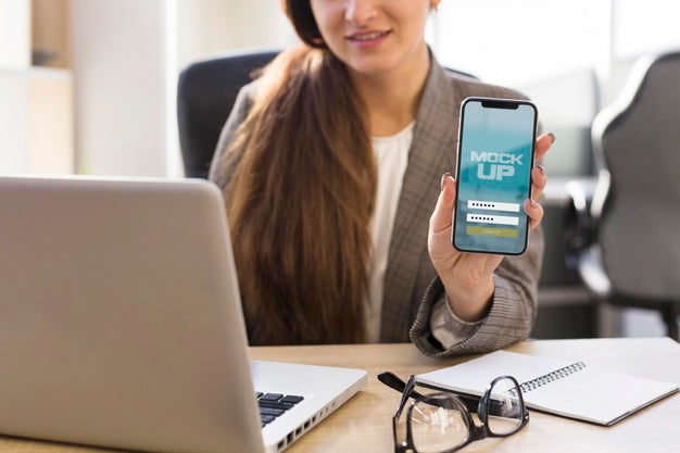 Young Woman Showing Her Phone Screen Mock-Up At Work Psd